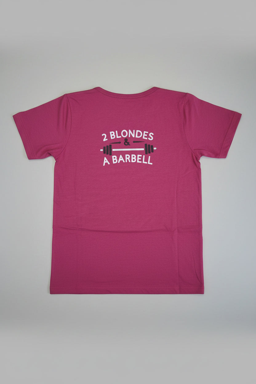 A pink short-sleeve t-shirt laid flat, showing the back side with a white graphic that reads '2 BLONDES & A BARBELL' around a barbell illustration.